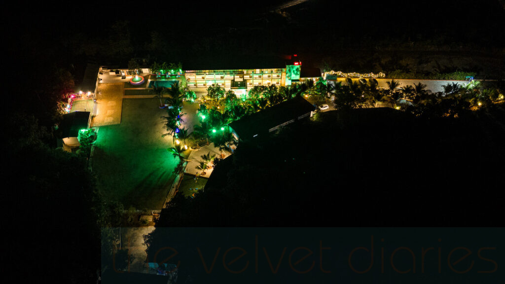 Aerial drone photograph of a resort at night showcasing landscape lighting, pool area and building layout in Mumbai.