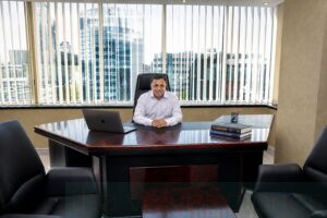 Environmental executive portrait of a business professional seated behind a large desk in a modern Mumbai office