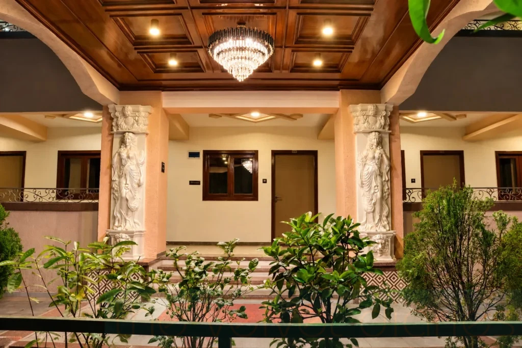 Architectural photography in Mumbai featuring a symmetrical property entrance with ornate columns, chandelier and landscaped greenery.