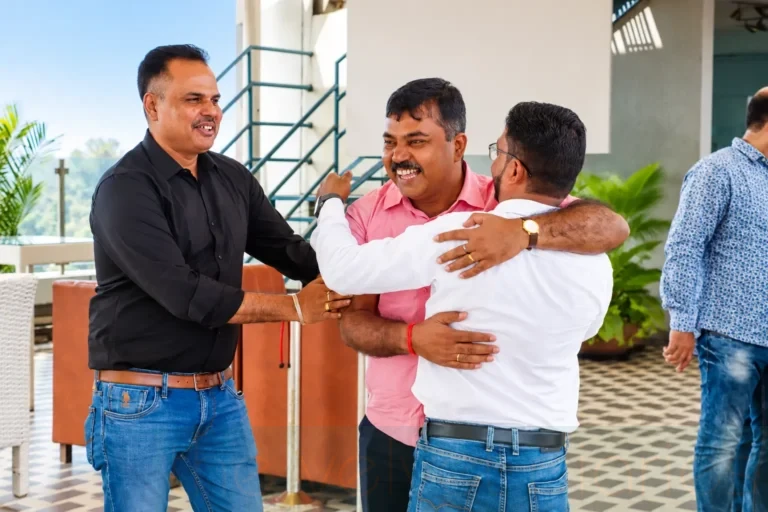 Corporate reunion event photography capturing colleagues greeting one another with a warm embrace during a professional alumni get-together.