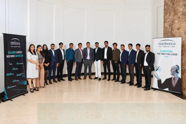 Corporate team photography showing Axe Finance employees standing together between branded company displays in a formal indoor setting.