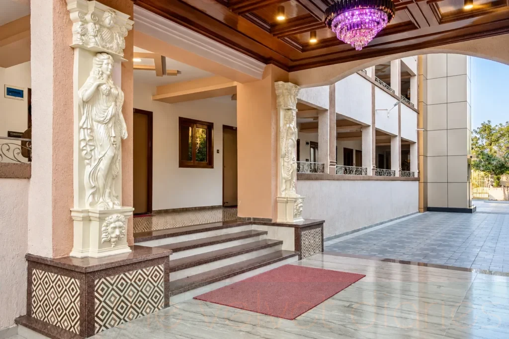 Hotel photography in Mumbai showcasing a classical entrance with sculpted columns, marble steps and a crystal chandelier.