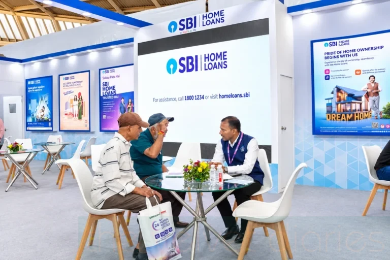 Exhibition photography showing an SBI Home Loans representative consulting visitors at a branded property expo booth, with promotional displays and customer seating.