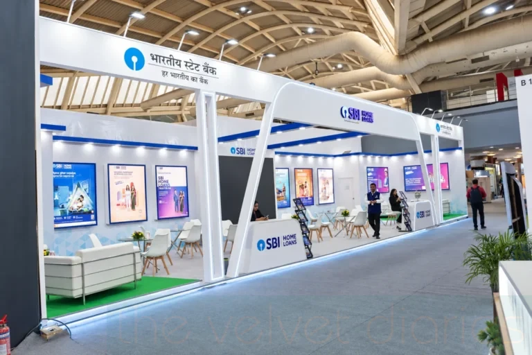 Trade show branding photography showing the full SBI Home Loans exhibition stand, illuminated structural framing, branded panels and consultation areas within an exhibition hall.